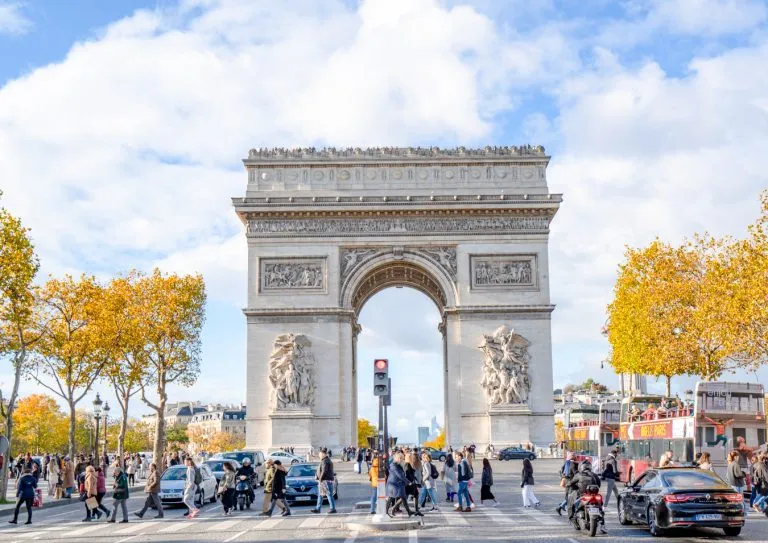 visit arc de triomphe paris france as seen from champs elysees with foliage on surrounding trees