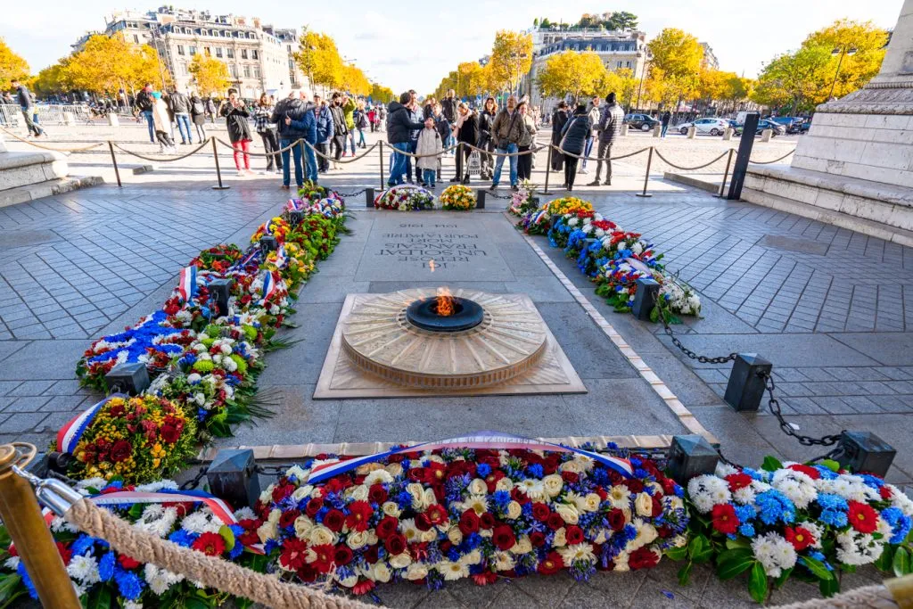tomb of the unknown solider under arc de triomphe paris surrounded by flowers