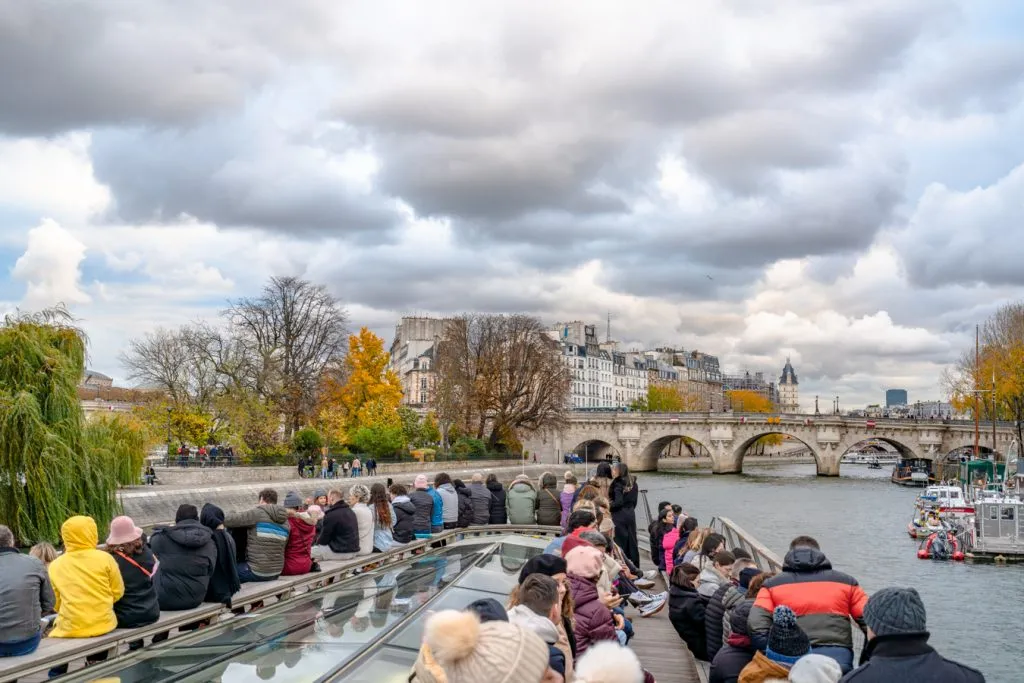 travelers on a seine river cruise with a bridge in the distance