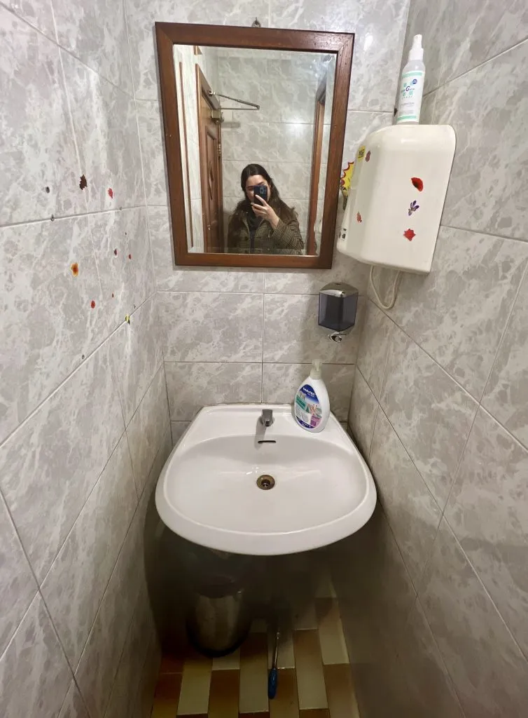 sink in a public toilet in europe with a pedal to turn it on on the floor