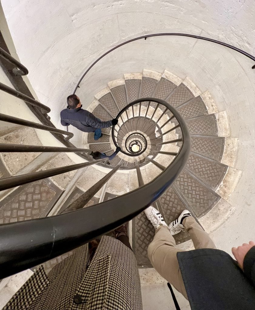 spiral staircase inside the arc de triomphe paris with feet in the image