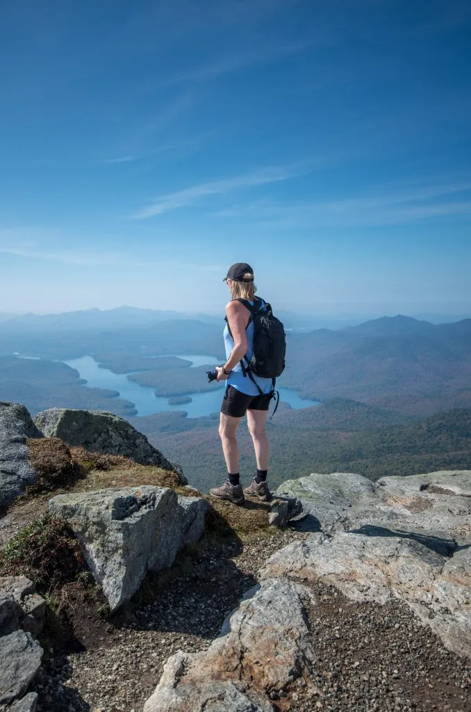 hiker at the top of whiteface mountain in new york, one of the fun places to go in usa summer trip ideas