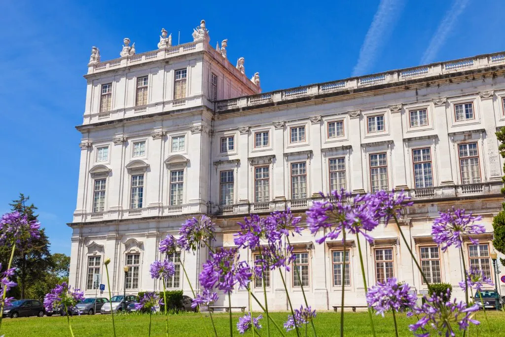 exterior facade of ajuda palace lisbon, with purple flowers in the foreground