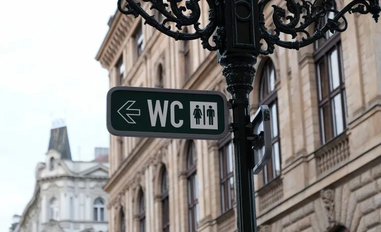 wc sign marking directions to public toilets in europe with city buildings in the background