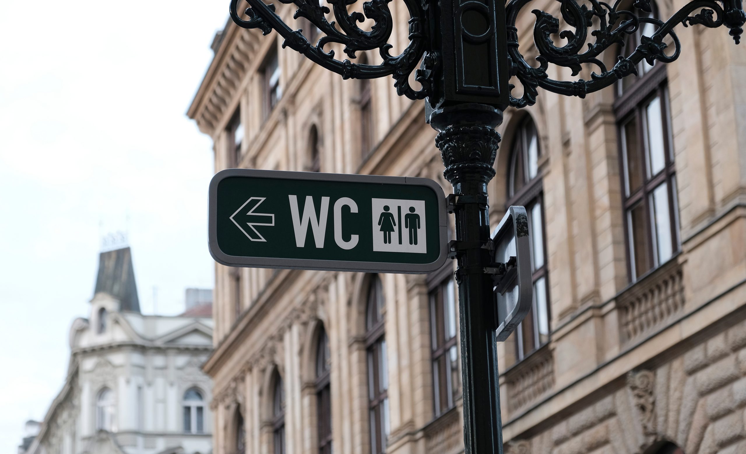 wc sign marking directions to public toilets in europe with city buildings in the background