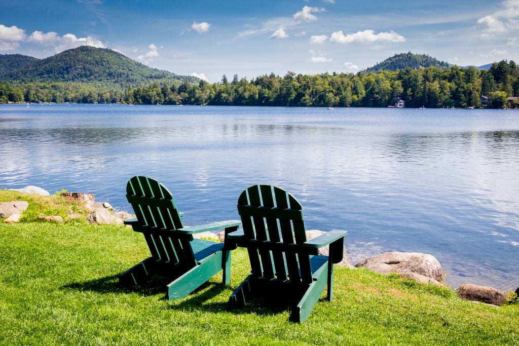 two adriondack chairs set up on the shore of lake placid, a cool usa summer vacation