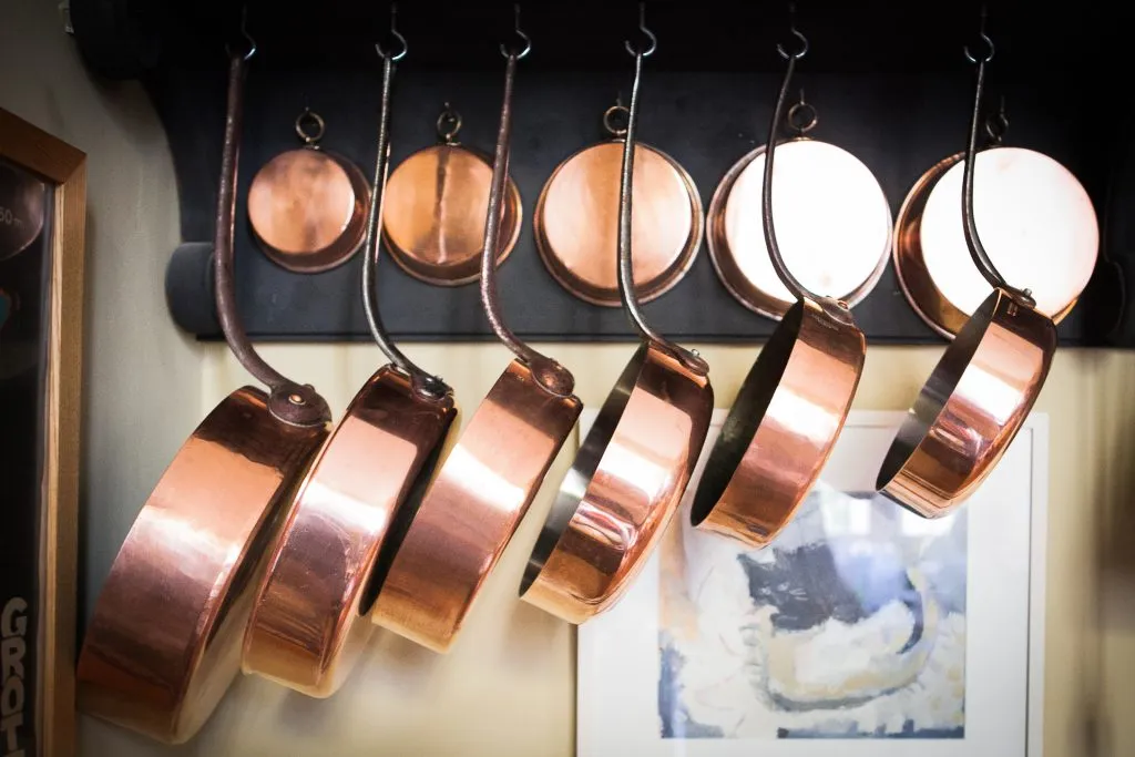 pots and pans hanging from the ceiling in a french kitchen