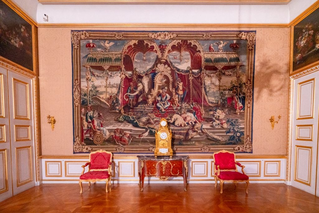 large tapestry hanging with some chairs in front of it in the munich residenz, one of the best things to do in munich one day itinerary