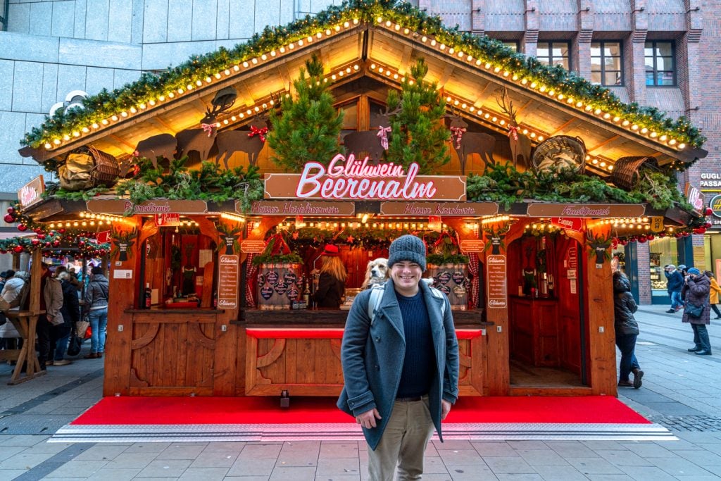 jeremy storm and ranger storm standing in front of a gluhwein stand at a munich christmas market, celebrating christmas in bavaria germany