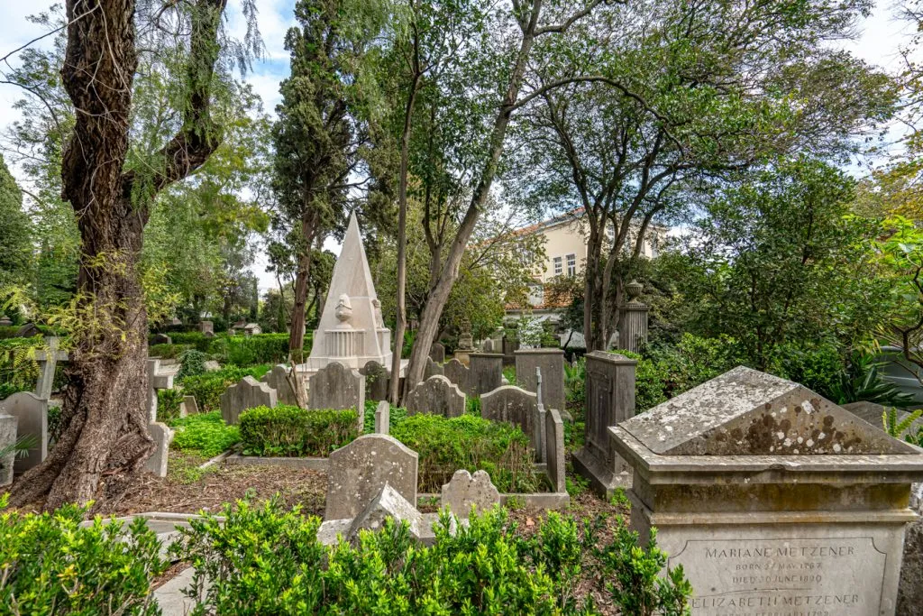 gravestones under shade trees in the british cemetery of lisbon estrela