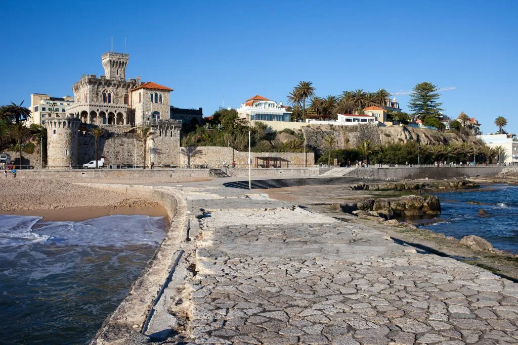 view of estoril portugal from a walkway into the water with castle in the background