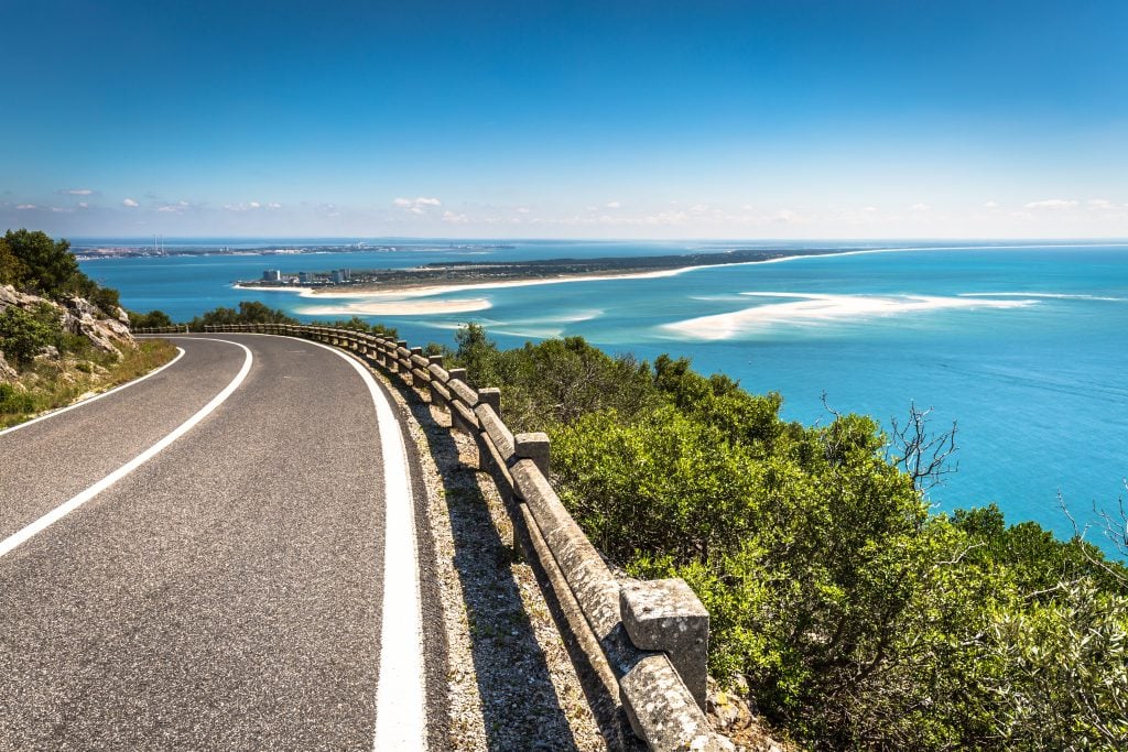 view from a scenic drive in arrabida natural park with road to the left and ocean visible in the background