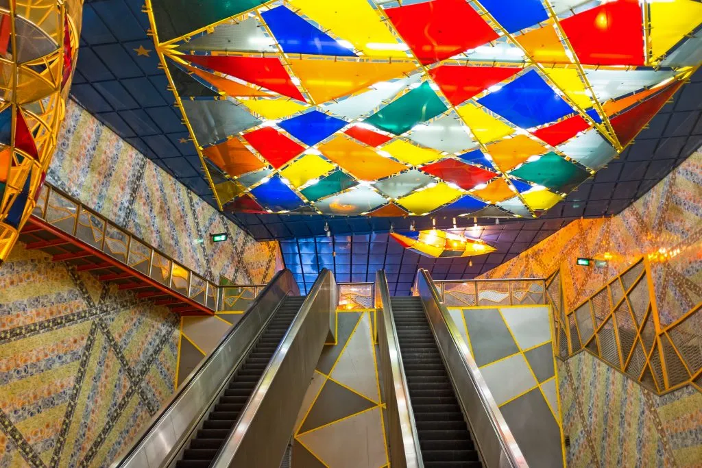 interior of olaias metro stop with escalators and colorful ceiling, one of the best hidden gems in lisbon portugal