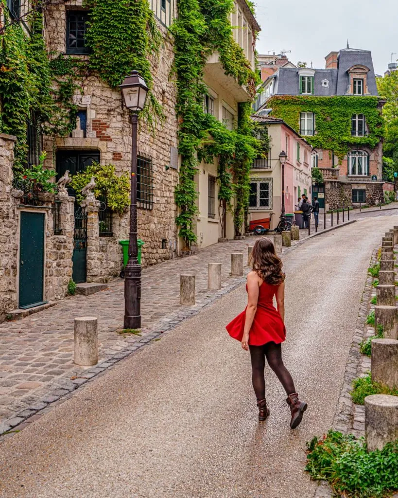 kate storm in a red dress on rue de l'abreuvoir, one of the best places to visit in montmartre paris