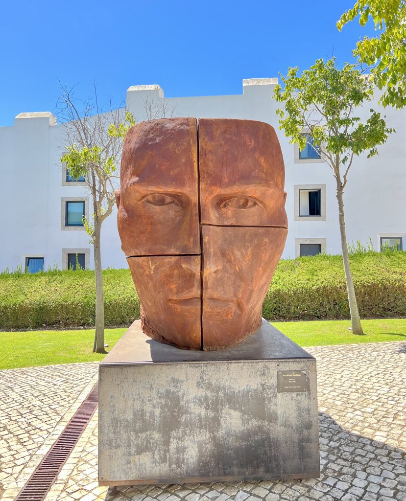 large bronze statue of a face displayed outdoors in the cascais citadel arts district, as seen on a lisbon to cascais day trip