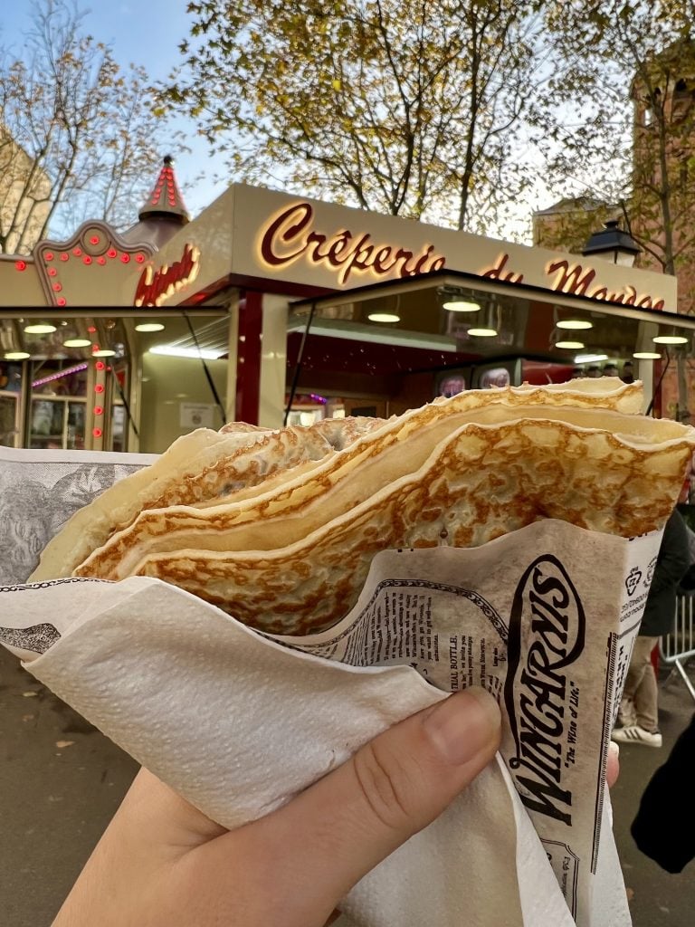 nutella crepe being held up in front of montmartre crepe stand