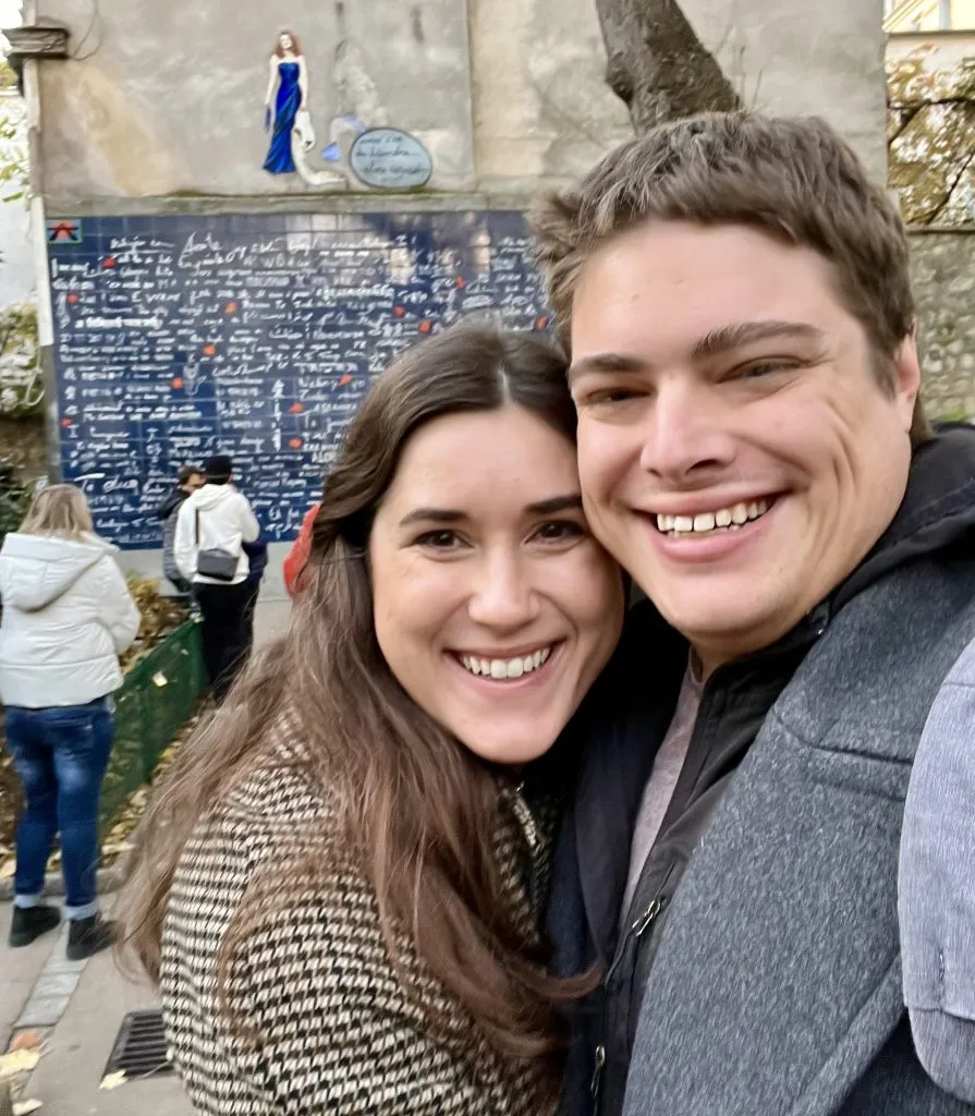 kate storm and jeremy storm taking a selfie in front of wall of love montmartre paris