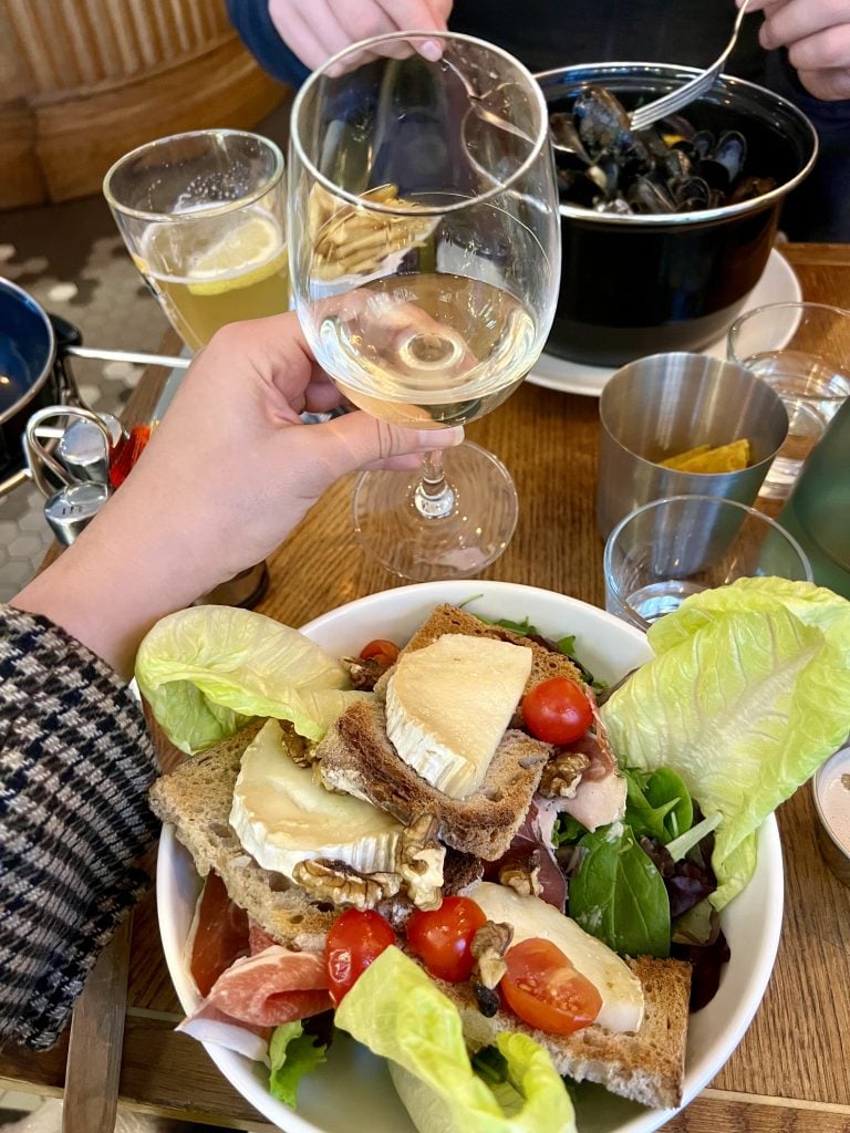 salad chevre chaud with glass of wine being held over it