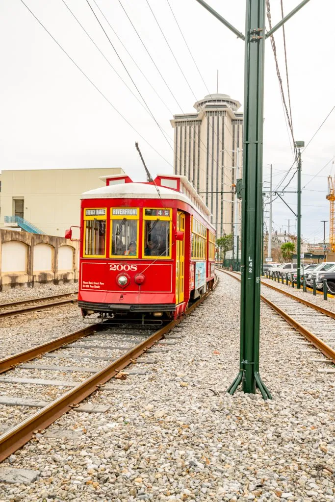 red new orleans street car traveling between the mississippi river and french quarter