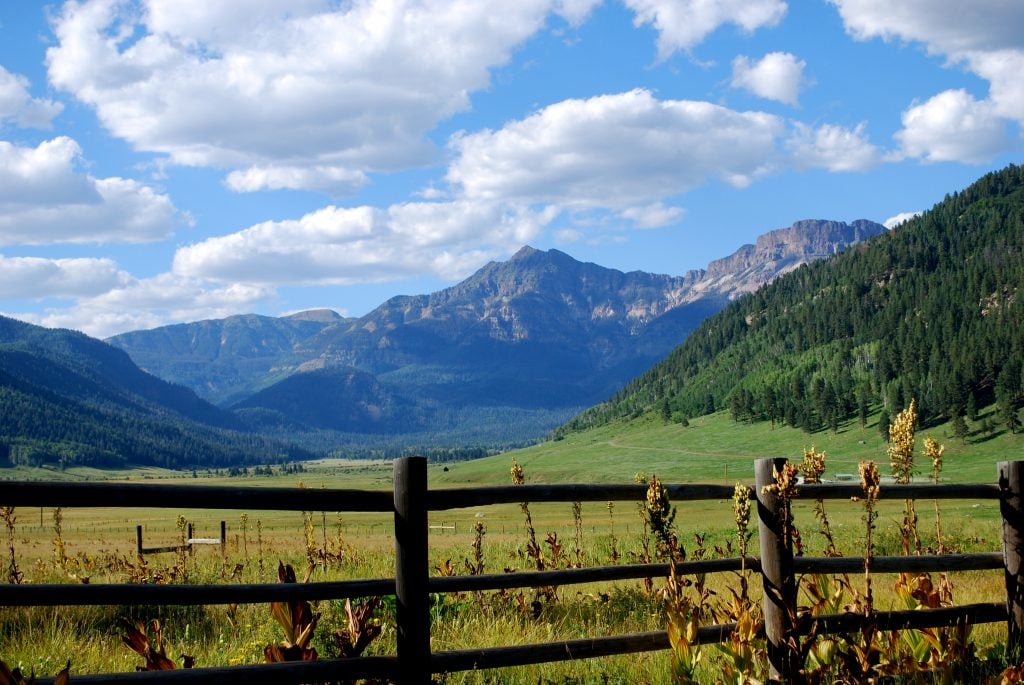 valley with a split rail fence in the foreground near pagosa springs co mountain towns