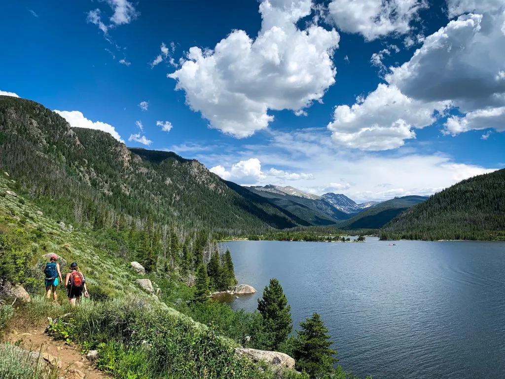 two people hiking along lake granby in the summer, located in granby one of the prettiest mountain towns in colorado