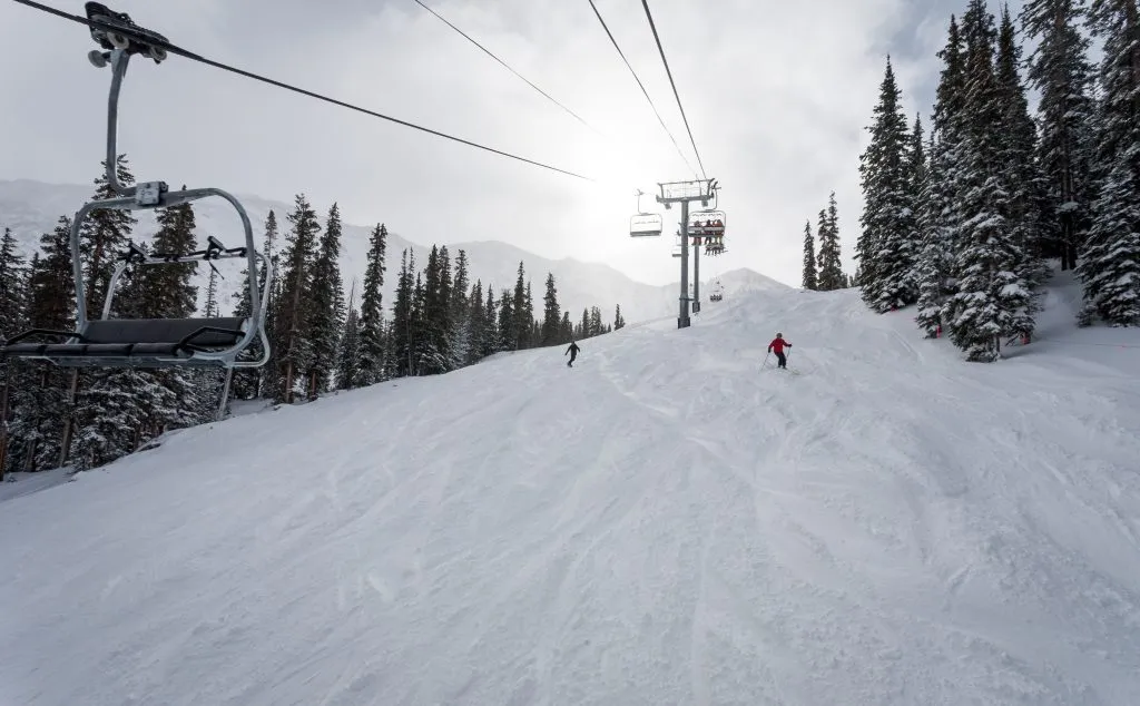 people downhill skiing in colorado with chairlift in foreground