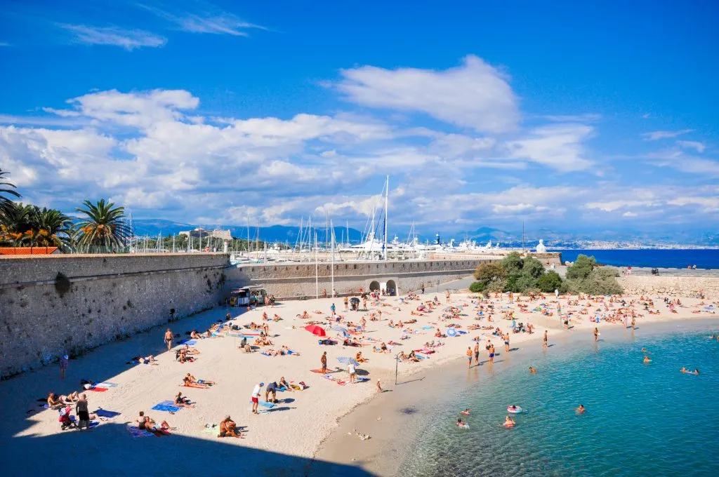 busy beach along city walls on a sunny day in antibes france