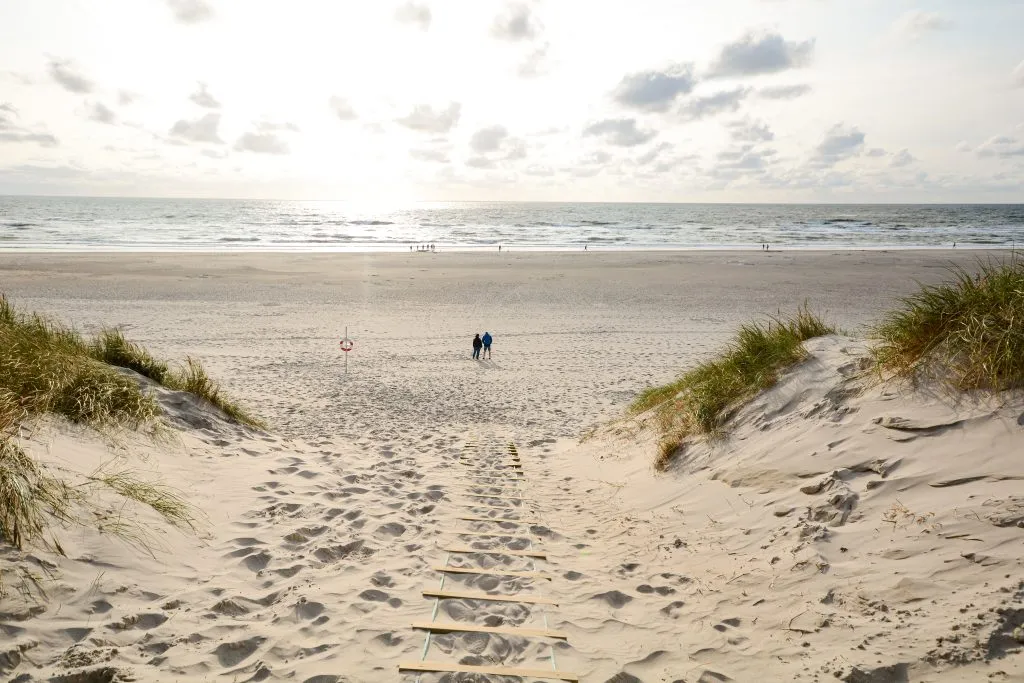 two people in the distance on a sandy beach at sunset near copenhagen, one of the best beach cities in europe
