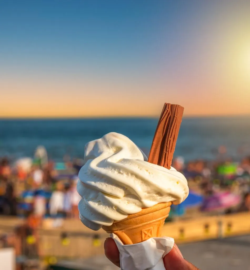 ice cream cone being held up in front of bournemouth england beach at sunset in summer