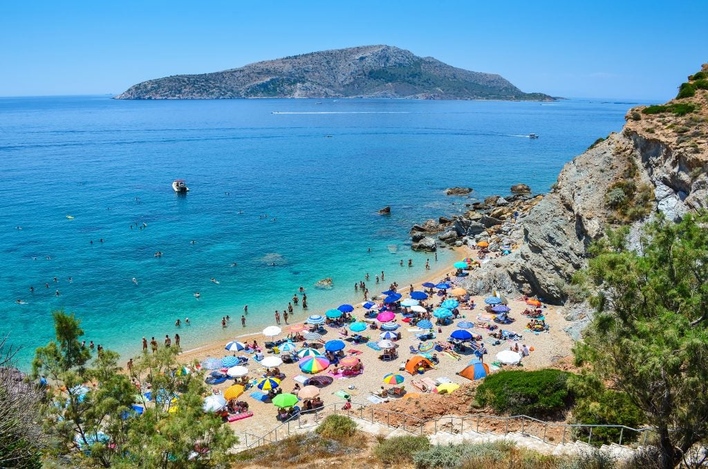 beach lined with colorful umbrellas near athens, one of the best europe cities beaches
