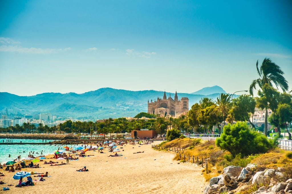 beach in palma spain with sand in the foreground and cathedral in the background