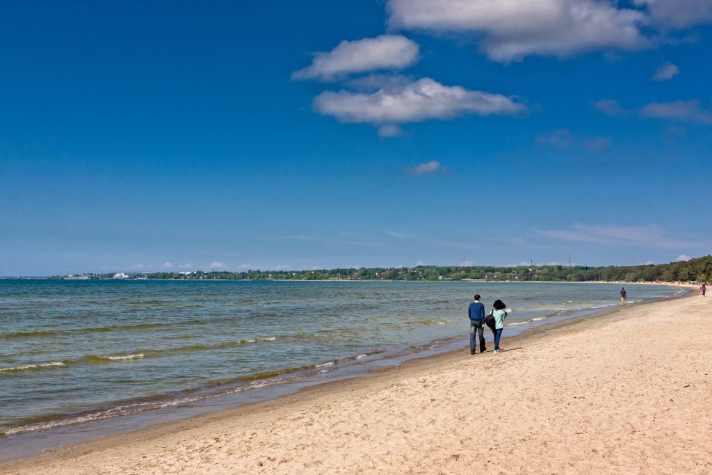 two people walking along a north sea beach in tallinn, one of the best coastal cities in europe to visit
