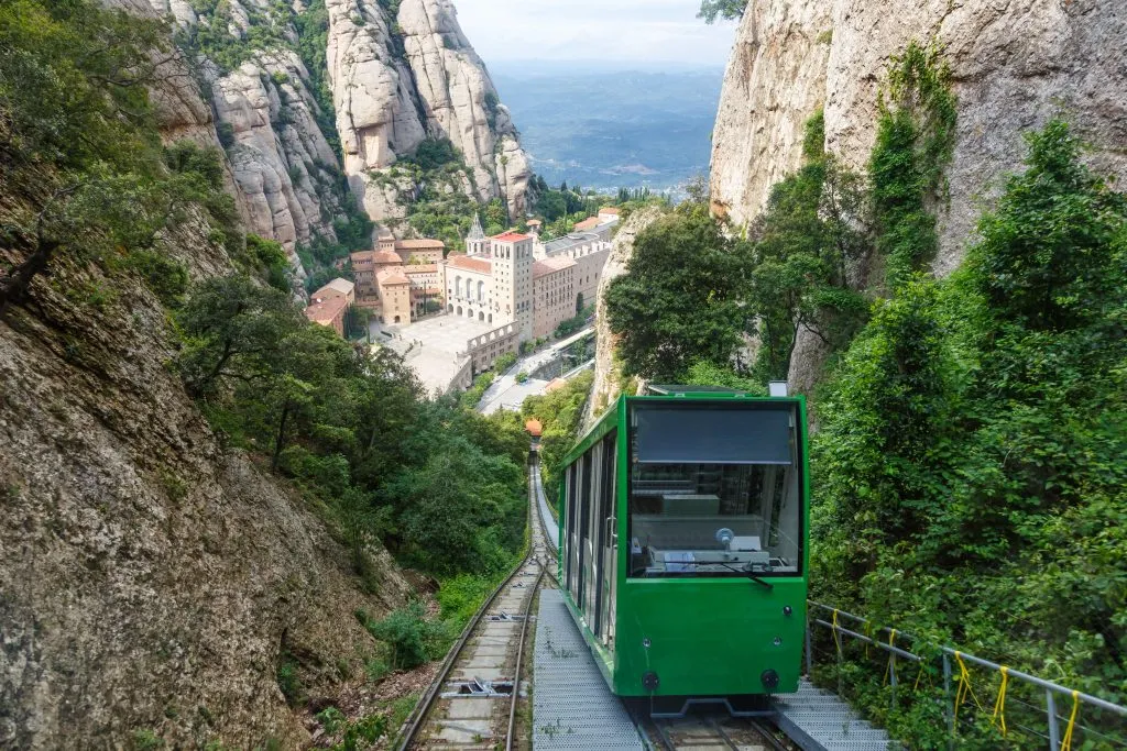 green cogwheel train climbing a mountain at montserrat, one of the top day trips barcelona spain