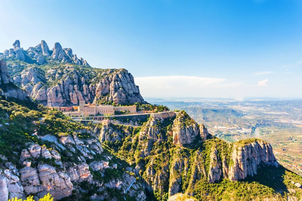 view of montserrat monastery from afar with mountains behind it, one of the best barcelona day trips