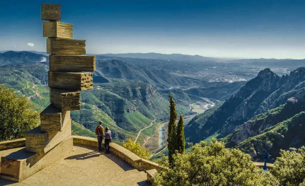 view of the mountains surrounding montserrat monastery with a sculpture in the foreground