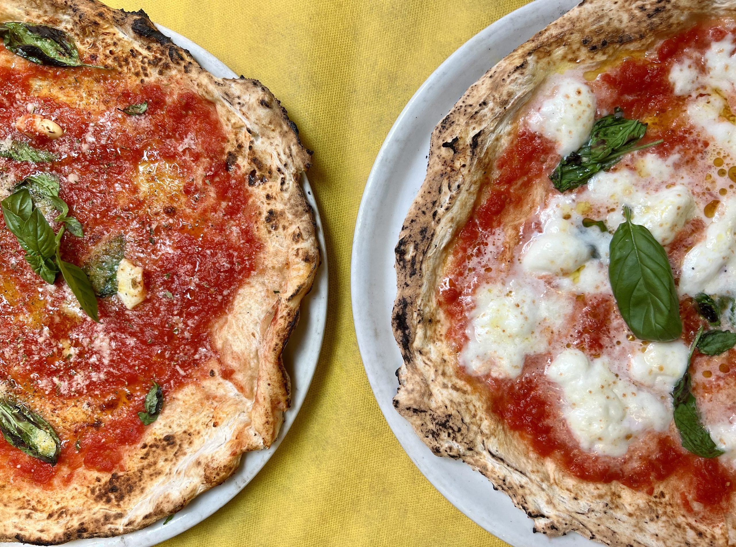 pizza marinara and pizza margherita lying next to each other on a table at a pizzeria in italy