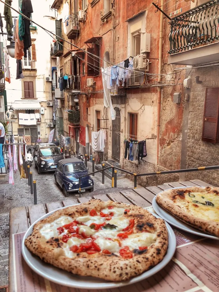 two napoli style pizzas in italy on a small street in naples