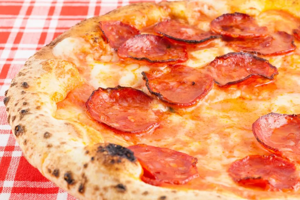 pizza diavola as seen from the side on a red checkered table cloth, italian pizza tips