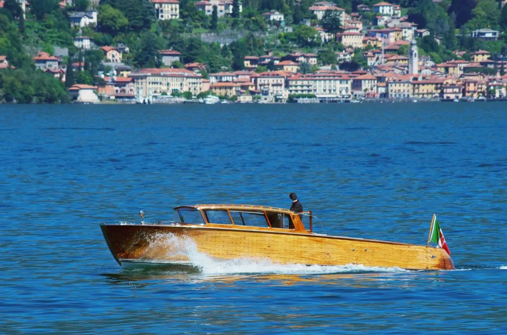 wooden speedboat cruising across lake como, a fun addition to a day trip from milan to lake como