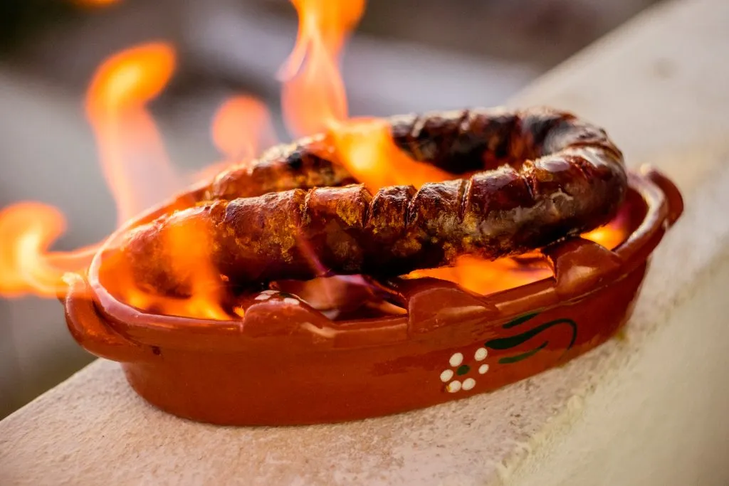 portuguese chourico sausage on fire, one of the best things to eat in lisbon portugal