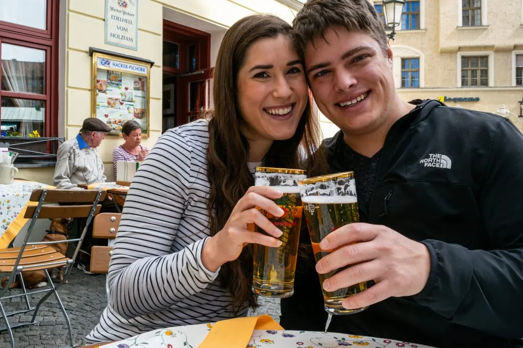kate storm and jeremy storm holding up beers during one day in munich germany