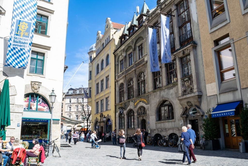 people walking down a street in the munich altstadt on a sunny day