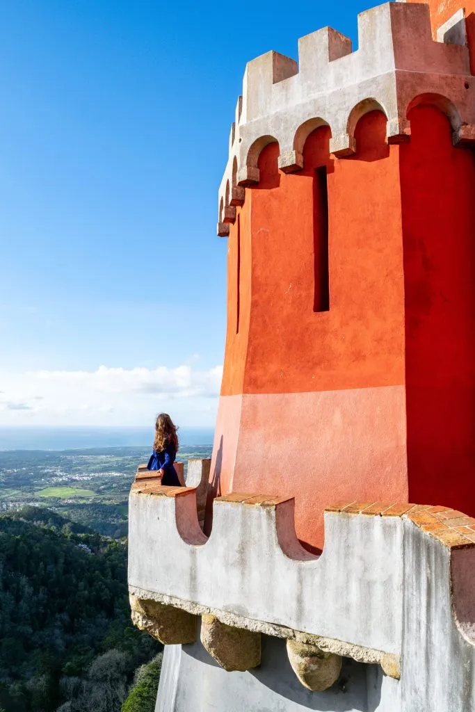 kate storm standing on one of the red pena palace terraces during one day in sintra itinerary