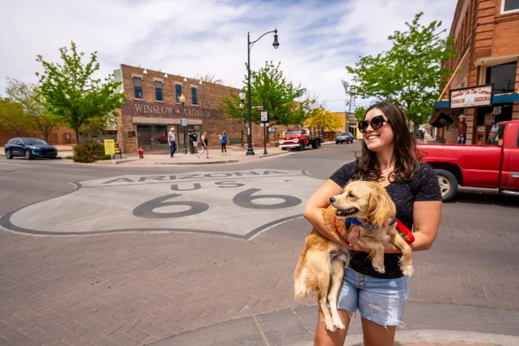 kate storm and ranger storm in front of route 66 sign in winslow arizona, one of the best small towns arizona places to go