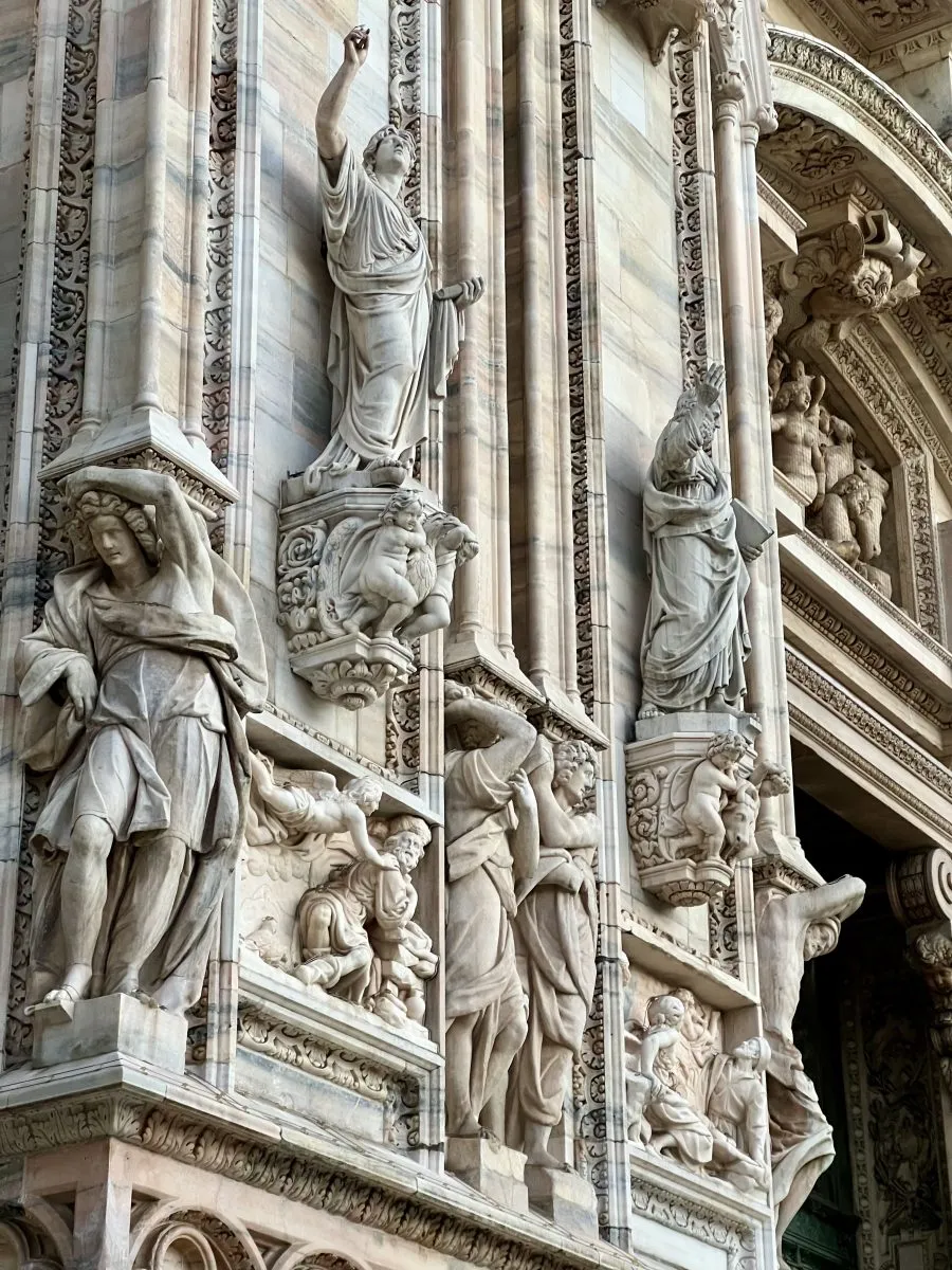 detailed carvings of people on the facade of the milan cathedral 