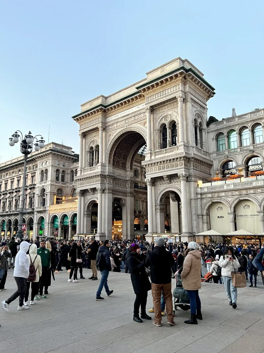 entrance of galleria vittorio emanuele ii during a crowded evening in milan cathedral square