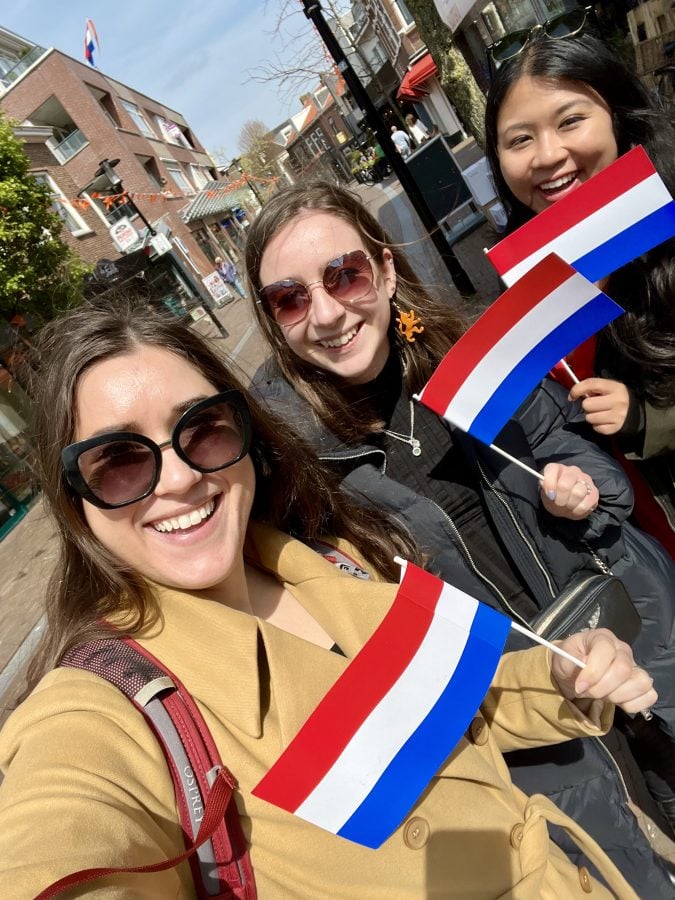kate storm sophie nadeau and christina guan holding up netherlands flags on kings day