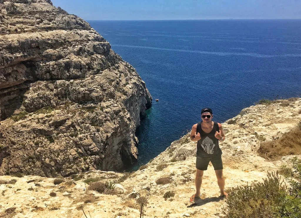 author billy of brb gone somewhere epic pictured on a cliff overlooking the sea when visiting the blue grotto malta
