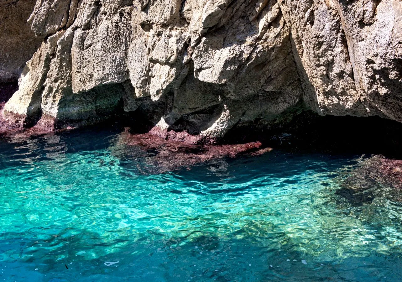 turquoise water against cliff base inside blue grotto malta
