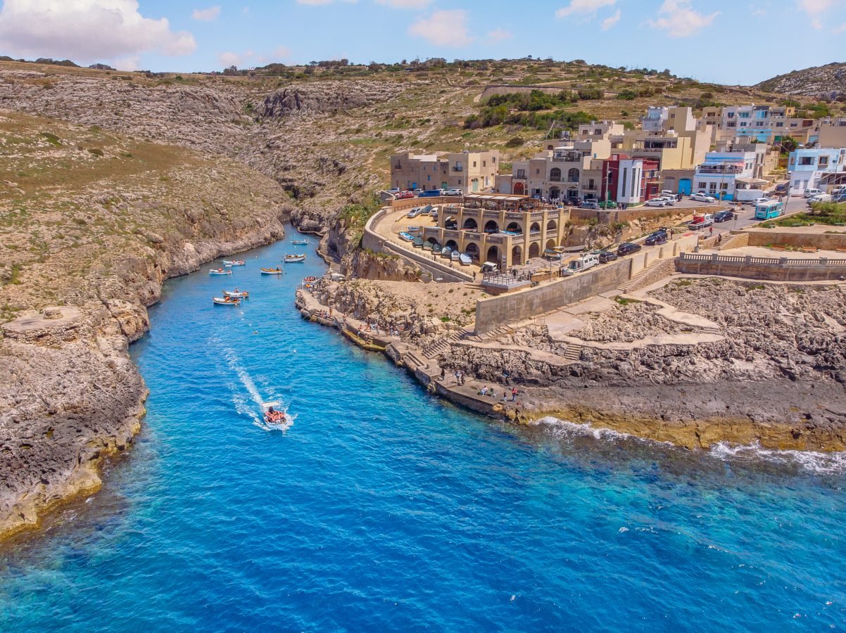 boats leaving village with tourists getting ready to visit blue grotto in malta